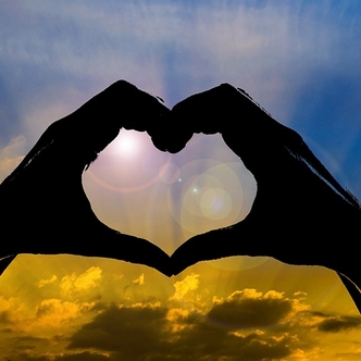 Finding a good wife: Hands held in a heart shape with sunlight shining behind